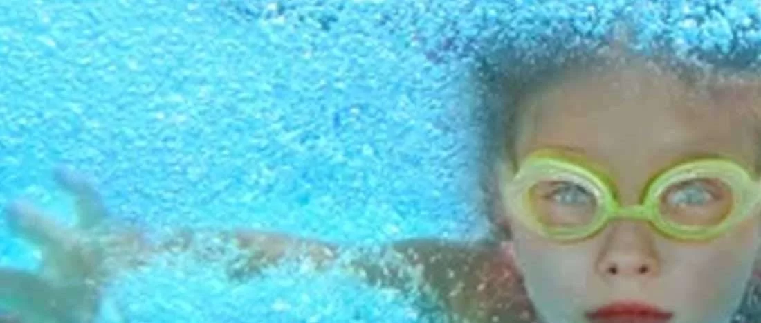 Meisje met zwembril zwemt onder water in Zwembad Oosterbeek